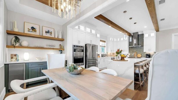 A modern kitchen with white cabinets, stainless steel appliances, and a wooden dining table. - Prescription for Paradise by Stay on 30a (Santa Rosa Beach)