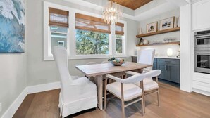 A modern kitchen with a dining area, wooden ceiling, and large windows. - Prescription for Paradise by Stay on 30a (Santa Rosa Beach)