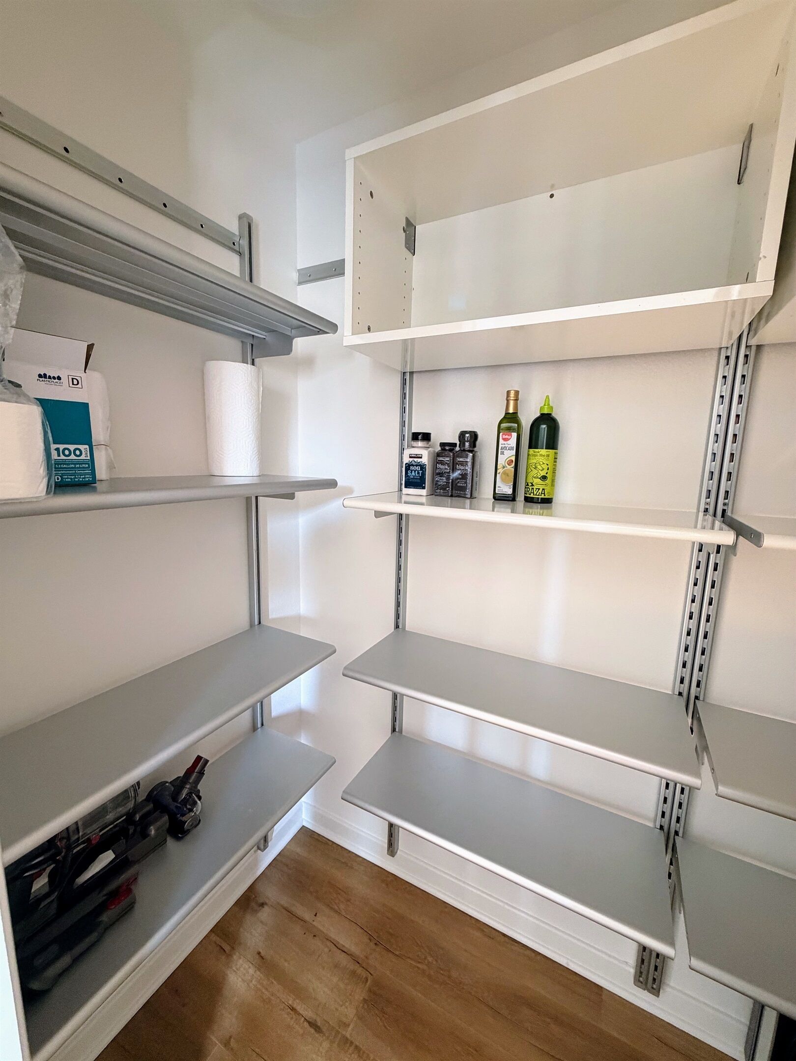 A clean, empty storage room with metal shelving units and a wooden floor.
