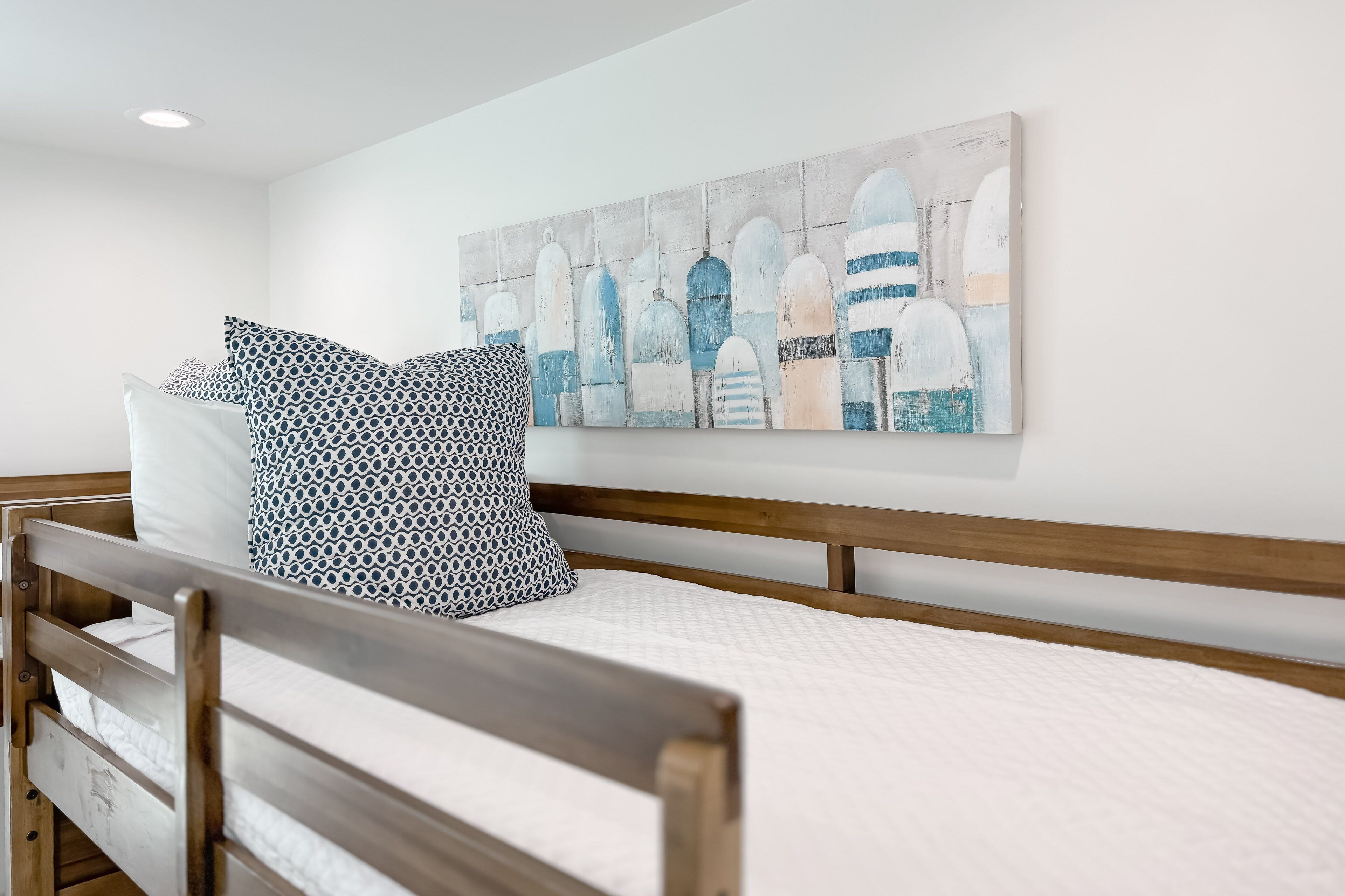 A bedroom with a wooden bed, white bedding, and a large abstract painting on the wall.