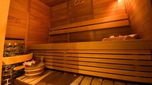 Una sauna de madera con bancos y pared de piedra.