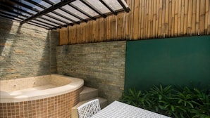 Zona de jacuzzi con suelo de baldosas, pared de madera y mesa con sillas.