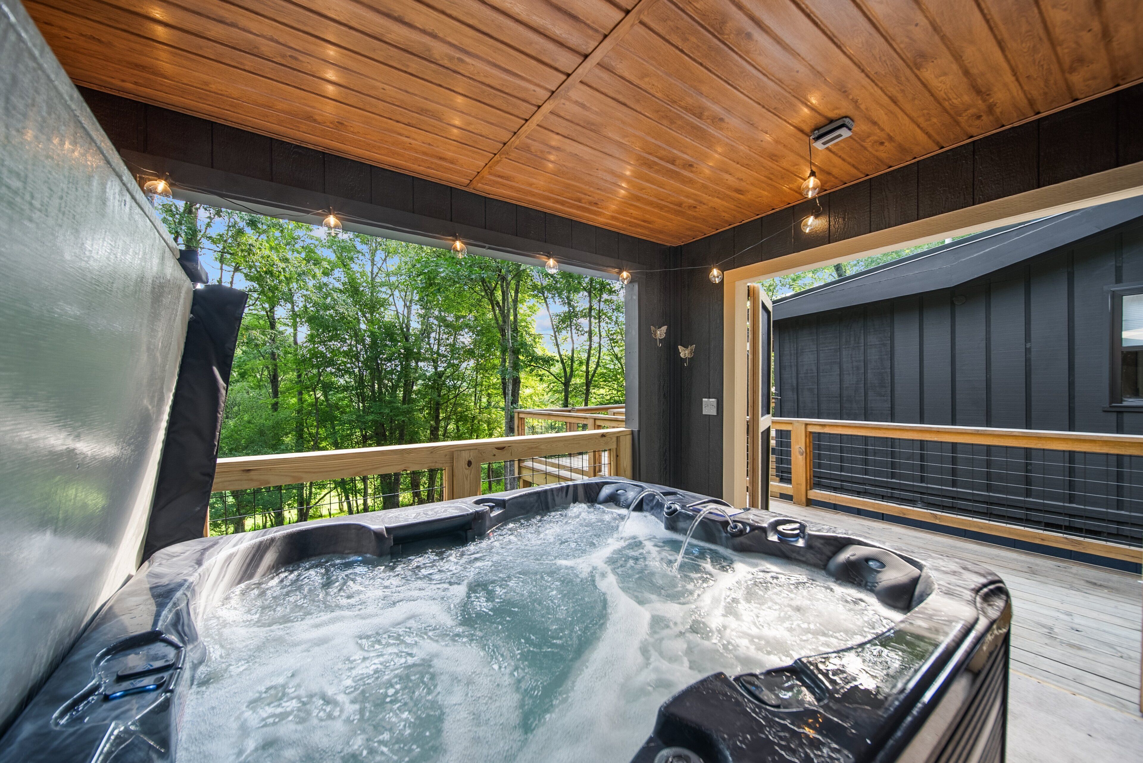 A hot tub on a wooden deck with a view of trees.