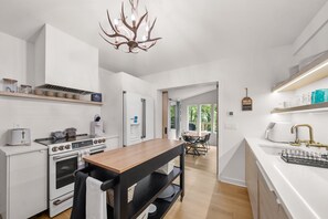 Una cocina moderna con horno empotrado, estufa y comedor con mesa y sillas.