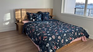 Una camera da letto con una testiera in legno, una coperta a fiori e una finestra con vista sugli edifici.