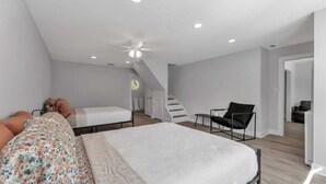 Ein modernes Schlafzimmer mit einem großen Bett, einem Sessel und einer Treppe, die in einen anderen Raum führt.