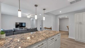 Eine moderne Küche mit Granit Arbeitsplatten, weißen Schränken und Pendelleuchten.