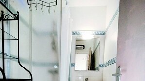 Un baño con ducha, lavamanos y espejo.