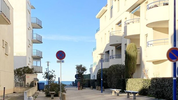 Una calle con un cartel de no estacionamiento, un banco y un edificio con balcones.