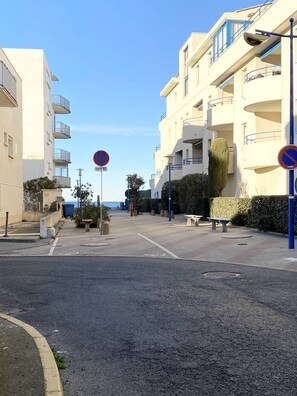 Una calle con un cartel de no estacionamiento, un banco y un edificio con balcones.