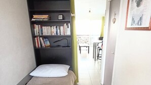 Un dormitorio pequeño y ordenado con una cama, una estantería y un escritorio.