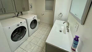 A compact laundry area with two washing machines, a toilet, and a sink with a mirror.