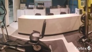 A gym with exercise equipment, a reception desk, and a view of the street outside. - PRIVATTO SUITES (Saltillo)