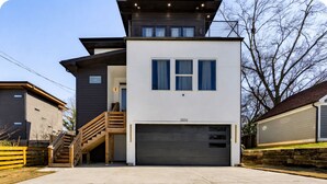 Ein modernes, zweistöckiges Haus mit Garage und Treppe, mit Blick auf die umliegende Wohngegend.
