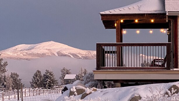 A wooden balcony with a railing, overlooking a snowy landscape and a mountain. - Come to the Mountains, Stay on the Farm - Cozy Farm-Stay Cottage (Bridesville)