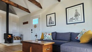 A cozy living room with a sofa, a wooden coffee table, and a fireplace. - Come to the Mountains, Stay on the Farm - Cozy Farm-Stay Cottage (Bridesville)