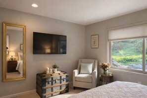 A bedroom with a bed, a chair, a dresser, a TV, and a window with a view of greenery. - Lovely 2-bedroom 2 Bath house in Carmel, perfect for a getaway (Carmel-by-the-Sea)