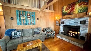 A cozy living room with a fireplace, a sofa set, and a patterned armchair. - Kayak on Prospect Lake, Paddle Boards, Swim Dock+! (Egremont)