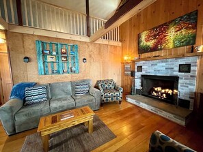 A cozy living room with a fireplace, a sofa set, and a patterned armchair.