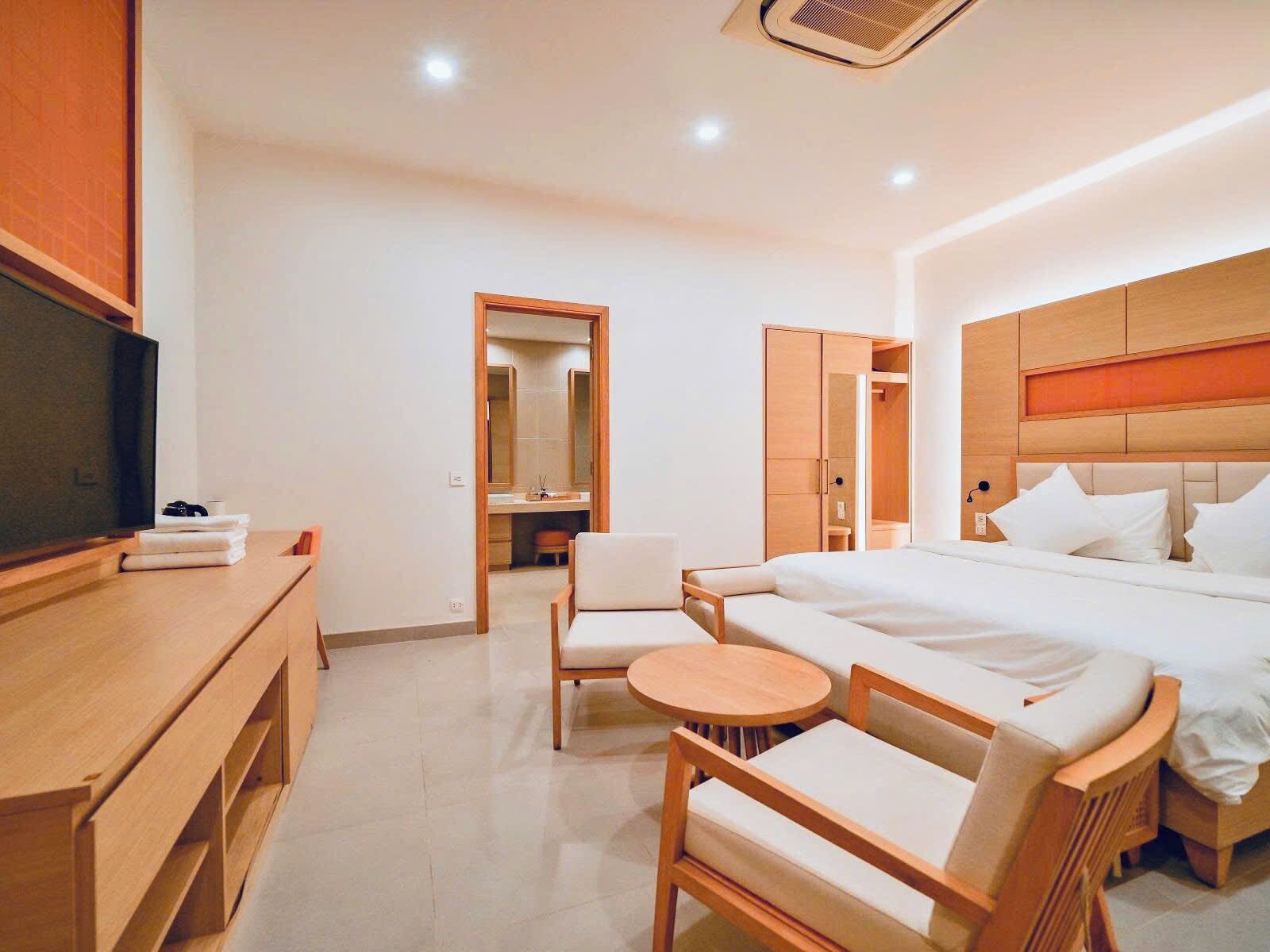 Habitación de hotel con cama, televisión, escritorio, silla y una mesita redonda.