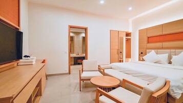 Habitación de hotel con cama, televisión, escritorio, silla y una mesita redonda.