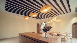 Un intérieur moderne avec un bar en bois et un espace repas, des luminaires suspendus et une grande fenêtre.