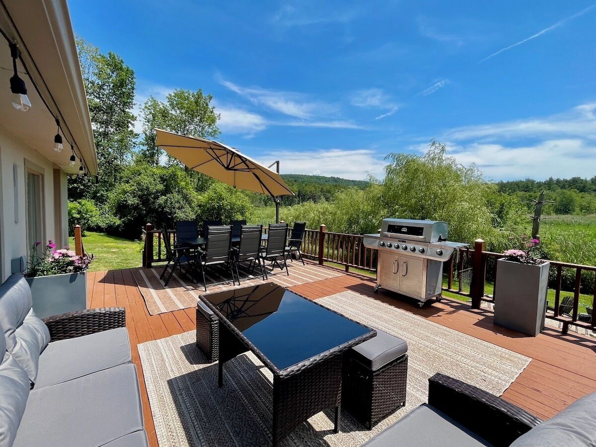 An outdoor patio with a grill, seating area, and a large umbrella.