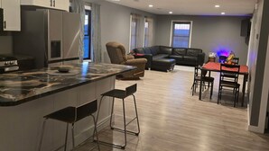 Una cocina moderna con una isla central, taburetes de bar y un comedor con mesa y sillas.