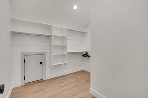 Une pièce avec un plancher en bois, des murs blancs, une porte et des étagères intégrées.