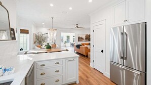 A modern kitchen with white cabinetry, a stainless steel refrigerator, and a central island with drawers. - Private Pool, Coastal Cottonwood Retreat, Sleeps 13,  Beach Access (Inlet Beach)