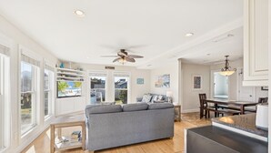 A spacious living area with a grey sofa, wooden coffee table, and a dining table with chairs. - 8388 Family Island Retreat | Steps to Beach (Avon)