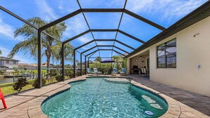 A swimming pool with a glass enclosure, lounge chairs, and a view of a lake. - Canalfront Island Escape with Pool, Lanai & Dock - Antigua Villa - Roelens (Cape Coral)