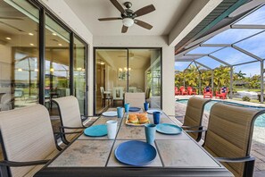 Un área de comedor al aire libre con una mesa dispuesta para dos personas, sillas y vistas a la piscina.