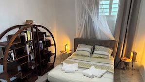 Un dormitorio ordenado con una cama, una estantería y dos mesitas de noche con lámparas.