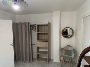 Ein Zimmer mit Kleiderschrank, Spiegel und Stuhl.