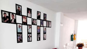 A room with a red sofa, a wall with framed photos, and a tiled floor. - HOTEL URUMITA MAGICA (Valledupar)