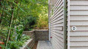 A narrow pathway flanked by a brick planter and a house with a 'D' sign. - Designer Inman Park | Beltline Steps (Atlanta)