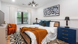 A bedroom with a bed, a nightstand, a dresser, a chair, and a large abstract painting on the wall. - Designer Inman Park | Beltline Steps (Atlanta)