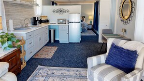 A compact hotel room with a kitchenette, a bed, a seating area, and a bathroom. - The Nest ~ Near Music Park + Lake Views (Live Oak)