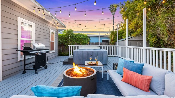 Eine Terrasse im Freien mit Grill, Feuerstelle, Sofa und Lichterketten.