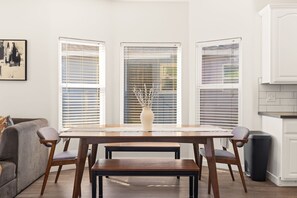 A dining area with a wooden table, four chairs, and a vase on the table. - Point Loma Cozy Retreat - Spa l AC l Parking (San Diego)