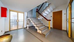 A modern interior with a spiral staircase, a large window, and a door.