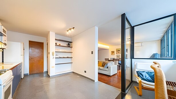 A modern apartment with a kitchen, a living area with a sofa, and a dining area.