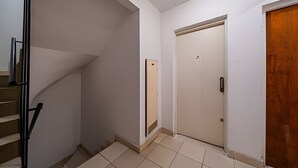 Un pasillo con una escalera, una puerta y una puerta de madera.