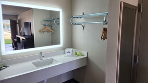 Une salle de bain avec un lavabo blanc, un miroir, un porte-serviettes et une porte de douche.