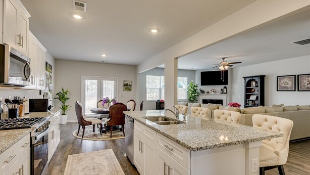 Una cocina moderna con encimeras de granito, muebles blancos y una isla central.