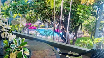 Un balcone con vista su una piscina, immerso nel verde e con piante in vaso.