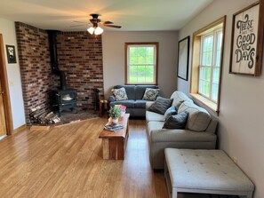 A cozy living room with a fireplace, a sofa, a coffee table, and a window.