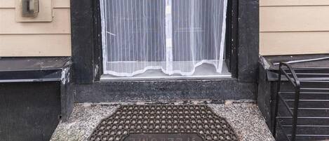 A house entrance with a black door, a mesh screen, and a welcome mat.