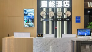 A hotel reception desk with a digital screen, multiple clocks, and a sign with Chinese characters. - XINGHEHOTEL (Xi'an)